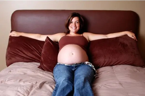 madre embarazada acostada sobre almohadas